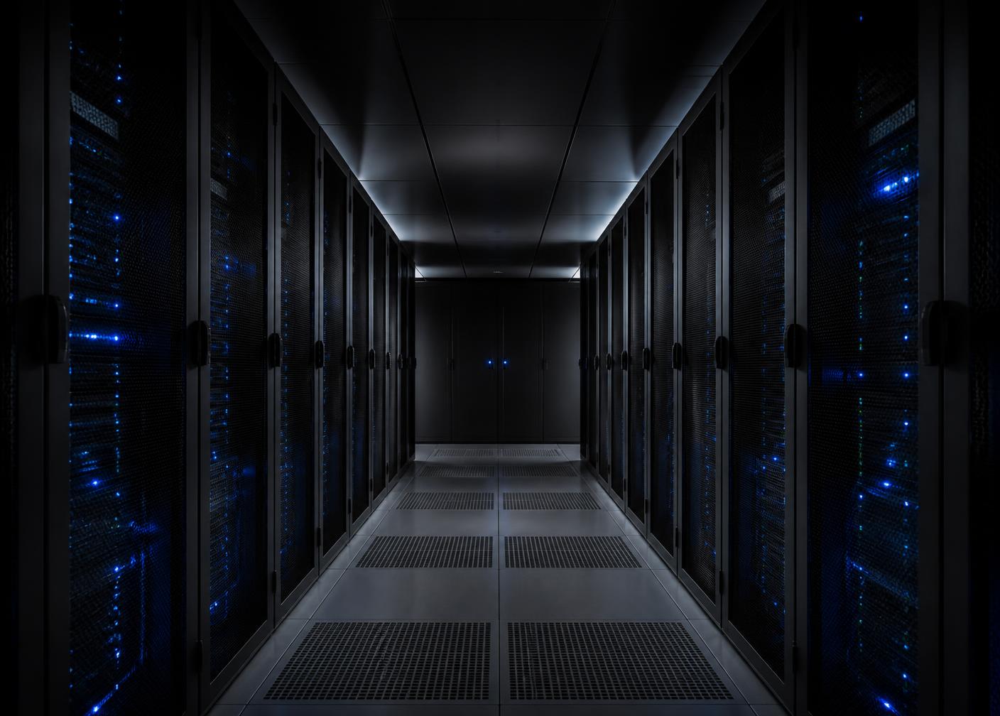 Rows of server racks with blue status lights in a cool, dimly lit data centre